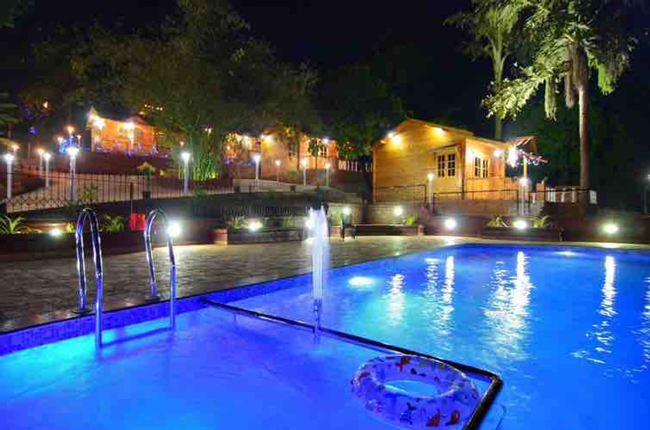 Night view of illuminated pool cozy woods hill resort goa