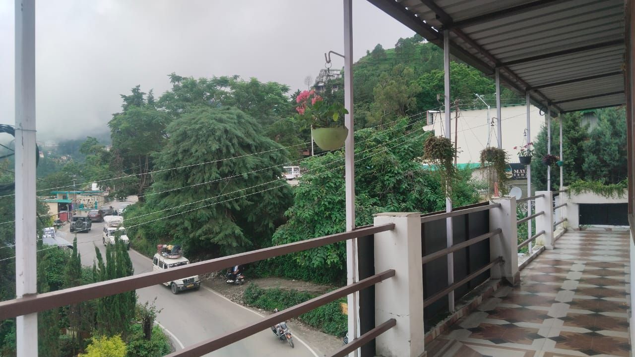 Covered balcony terrace framing scenic mountain roads and greenery in Bhimtal